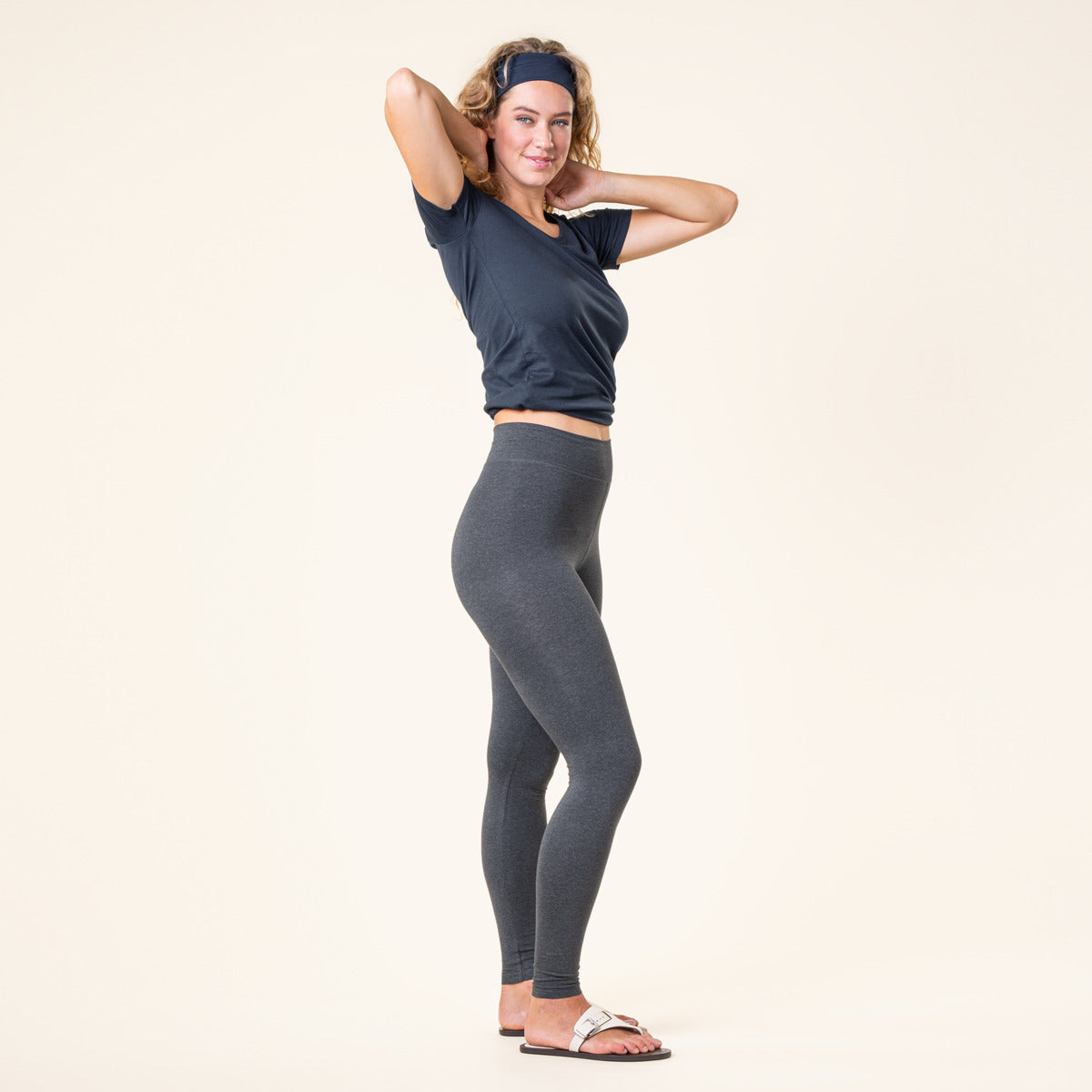 Woman wearing a black athletic top and grey organic cotton leggings on a beige background